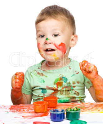 Little boy is playing with paints