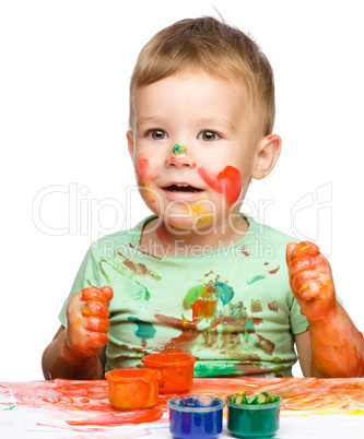 Little boy is playing with paints