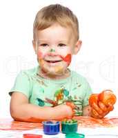 Little boy is playing with paints