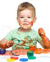 Little boy is playing with paints