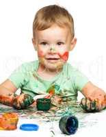 Little boy is playing with paints