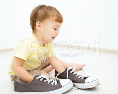 Boy is playing with big sneakers