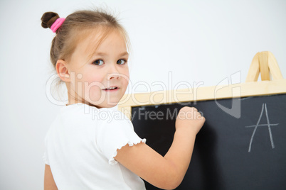 Little girl is writing on a blackboard