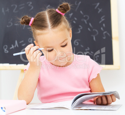 Little girl is writing using a pen