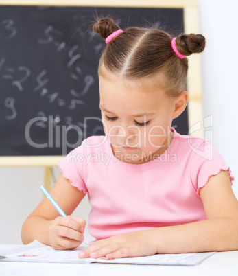 Little girl is writing using a pen