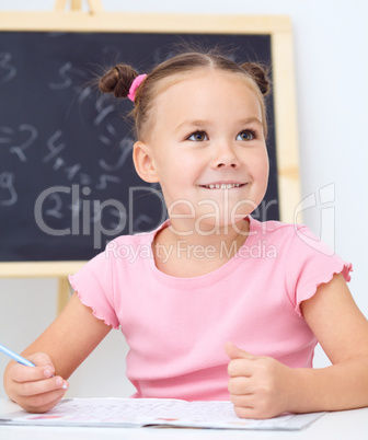 Little girl is writing using a pen