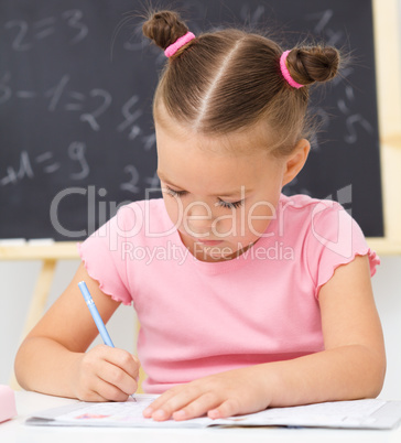 Little girl is writing using a pen