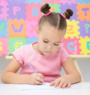 Little girl is writing using a pen