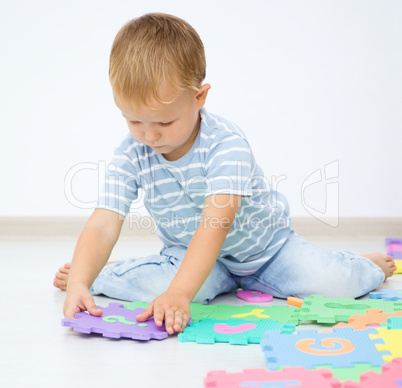 Little boy is putting together a big puzzle