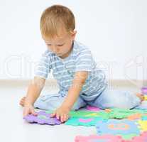 Little boy is putting together a big puzzle