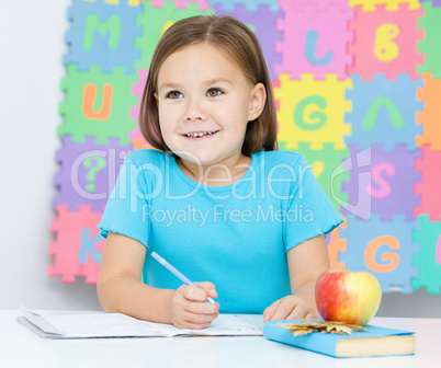 Little girl is writing using a pen