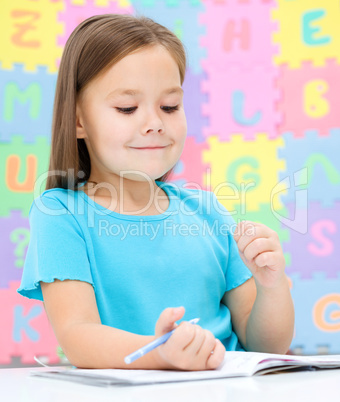 Little girl is writing using a pen