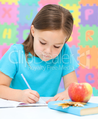 Little girl is writing using a pen