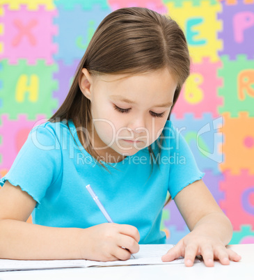 Little girl is writing using a pen