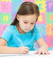 Little girl is writing using a pen