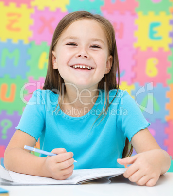 Little girl is writing using a pen