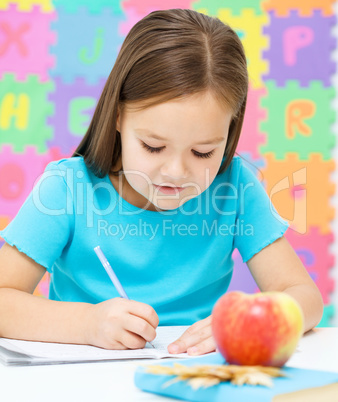 Little girl is writing using a pen