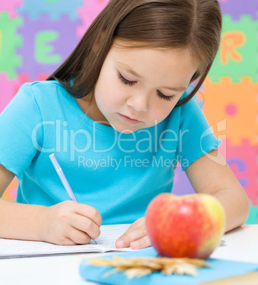 Little girl is writing using a pen