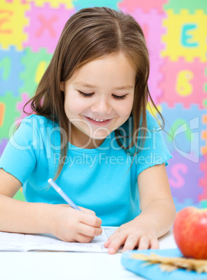 Little girl is writing using a pen