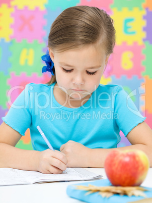 Little girl is writing using a pen