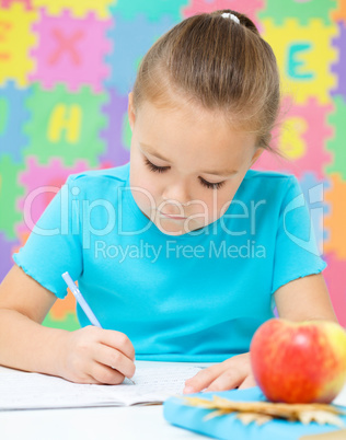 Little girl is writing using a pen