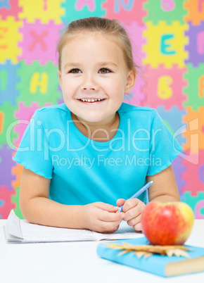 Little girl is writing using a pen