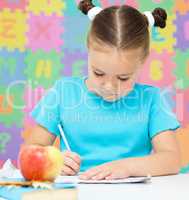 Little girl is writing using a pen