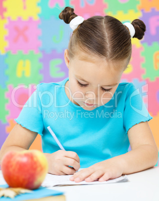 Little girl is writing using a pen