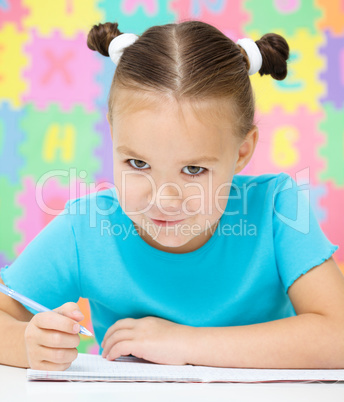 Little girl is writing using a pen