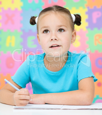 Little girl is writing using a pen