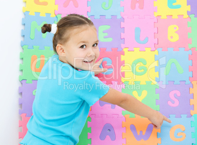 Little girl is pointing at letter G on alphabet