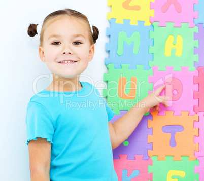 Little girl is pointing at letter O on alphabet