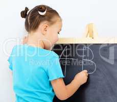Little girl is writing on a blackboard