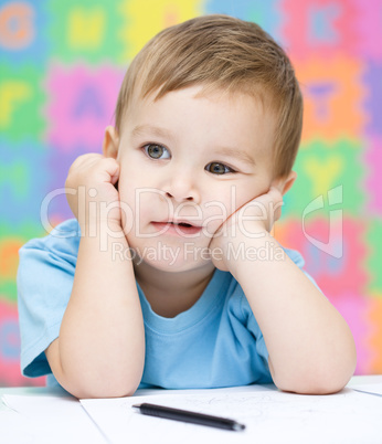 Little boy is writing on his copybook