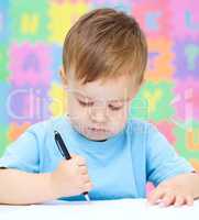 Little boy is writing on his copybook