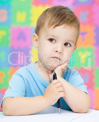 Little boy is writing on his copybook