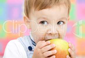 Little child is biting red apple