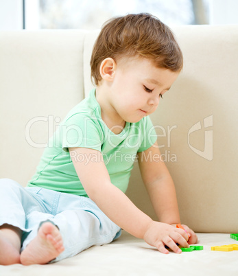 Boy is playing while sitting on couch