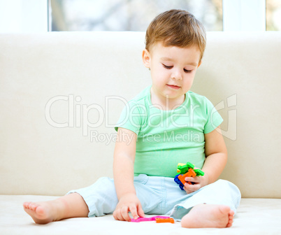 Boy is playing while sitting on couch