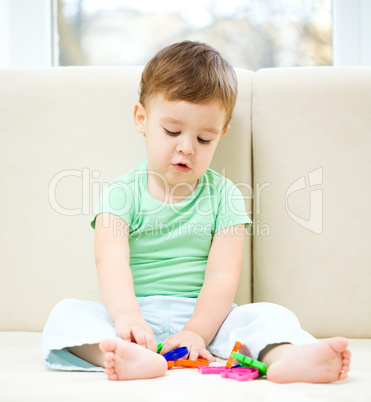 Boy is playing while sitting on couch