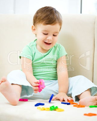 Boy is playing while sitting on couch