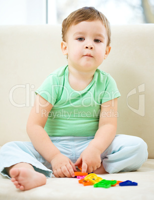 Boy is playing while sitting on couch