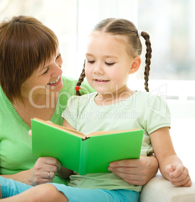 Mother is reading book for her daughter