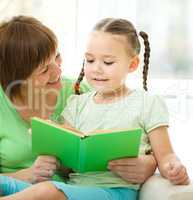 Mother is reading book for her daughter