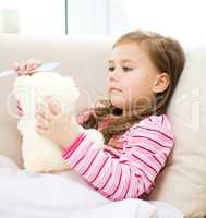 Little girl is combing her teddy bear