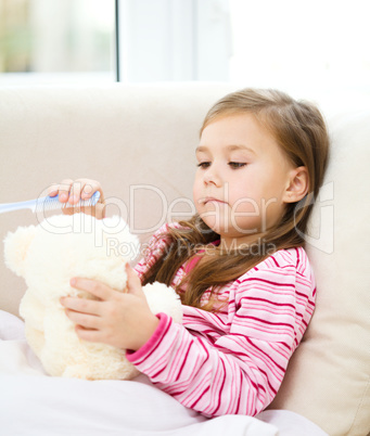Little girl is brushing her teddy bear