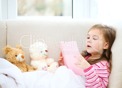 Little girl is reading a story for her teddy bears