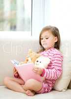 Little girl is reading a story for her teddy bears