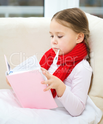 Ill little girl with thermometer is reading book