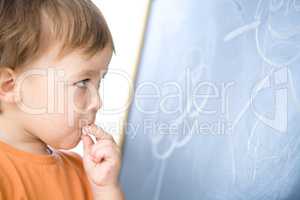 Little boy is biting chalk